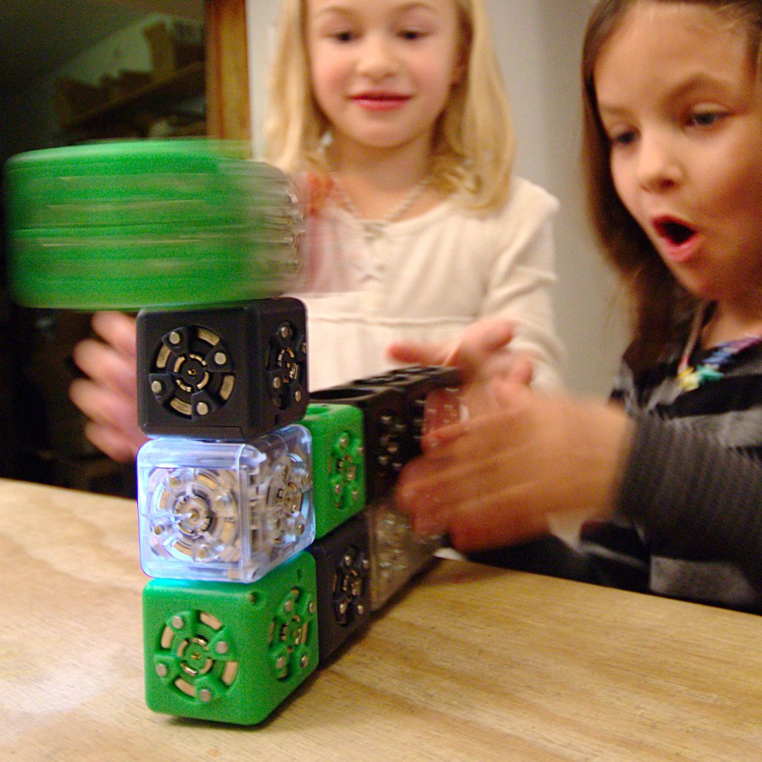 Two children reacting with delight to a spinning Cubelets robot