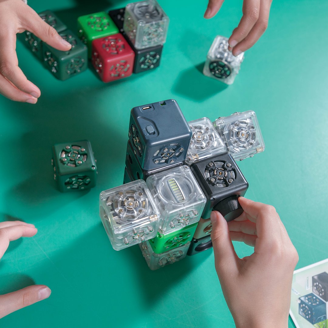 Multiple hands building with Cubelets robot blocks on a classroom table